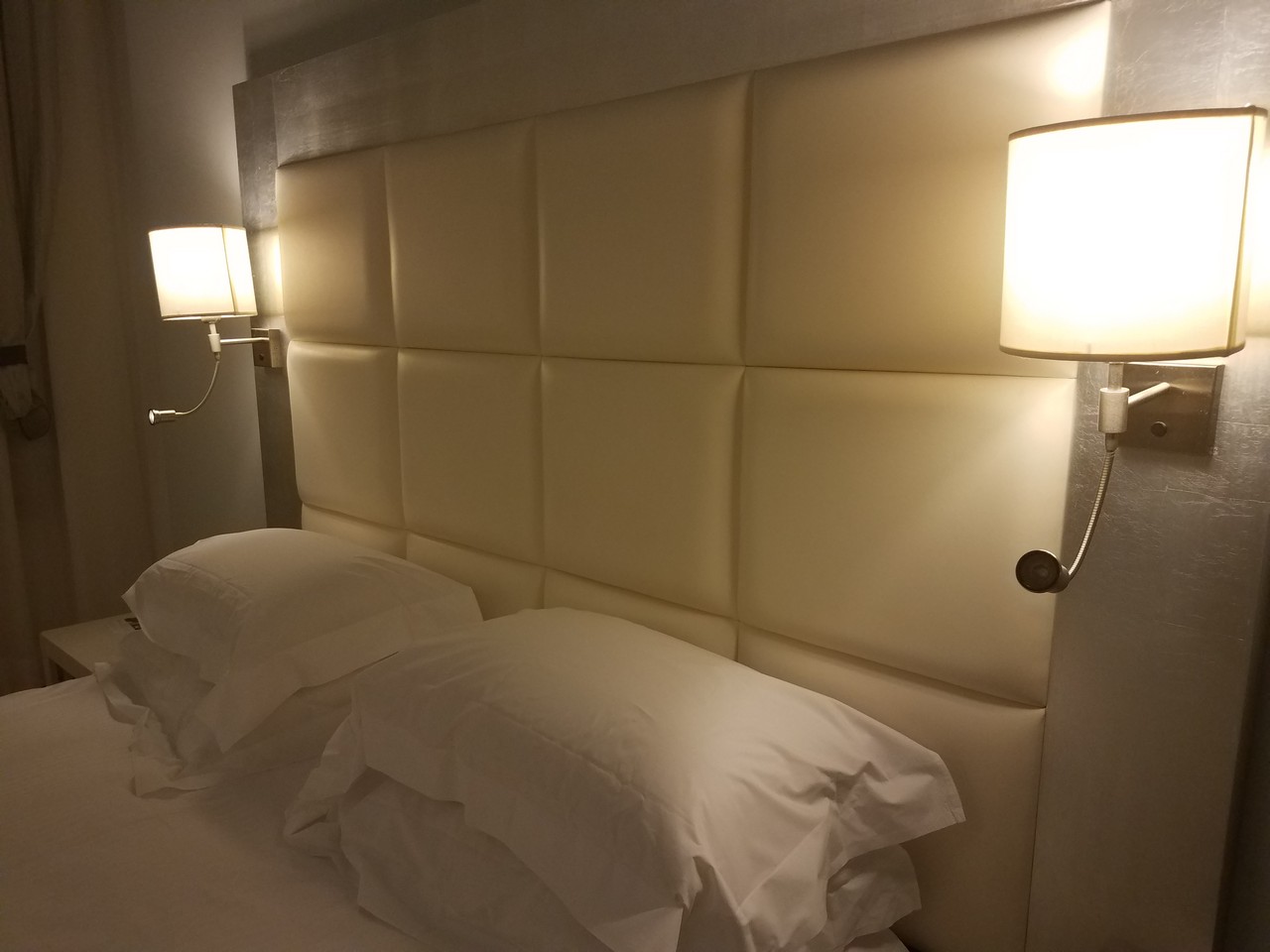 a bed with white pillows and lamps