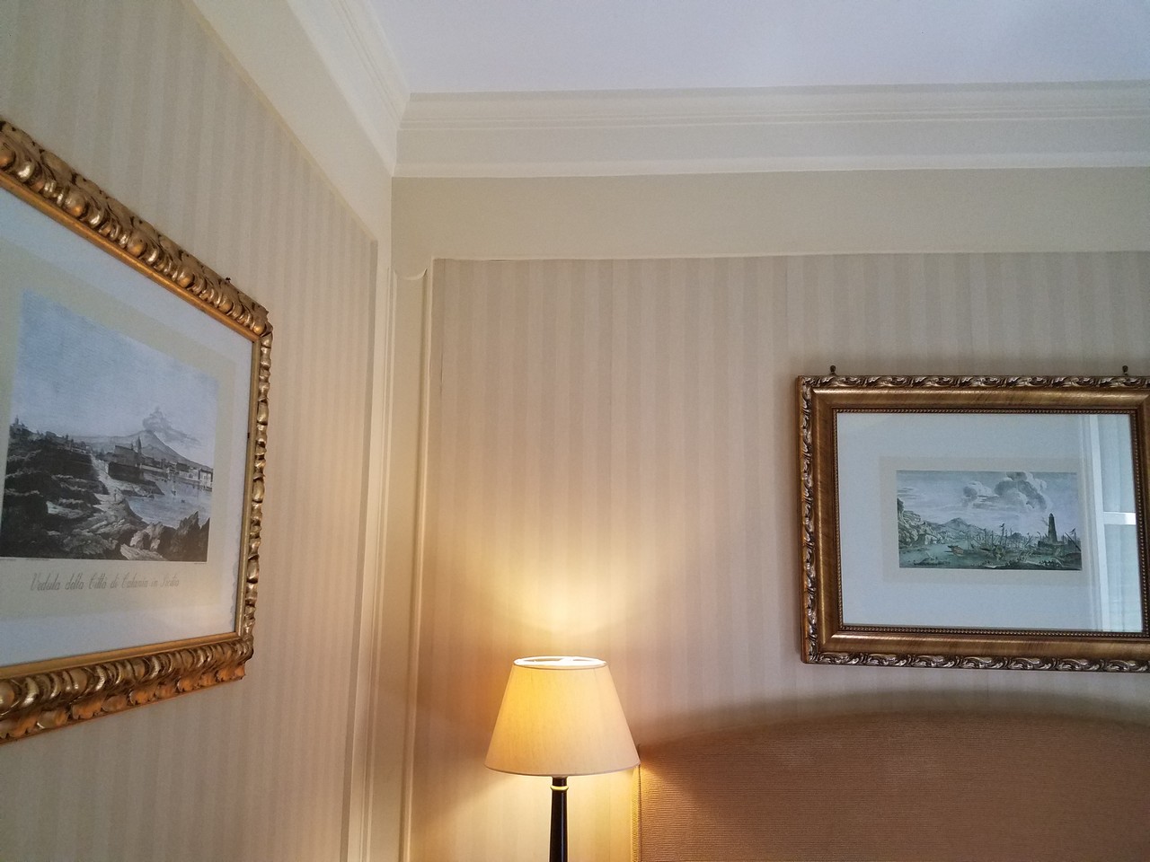 a lamp next to a bed with pictures on the wall