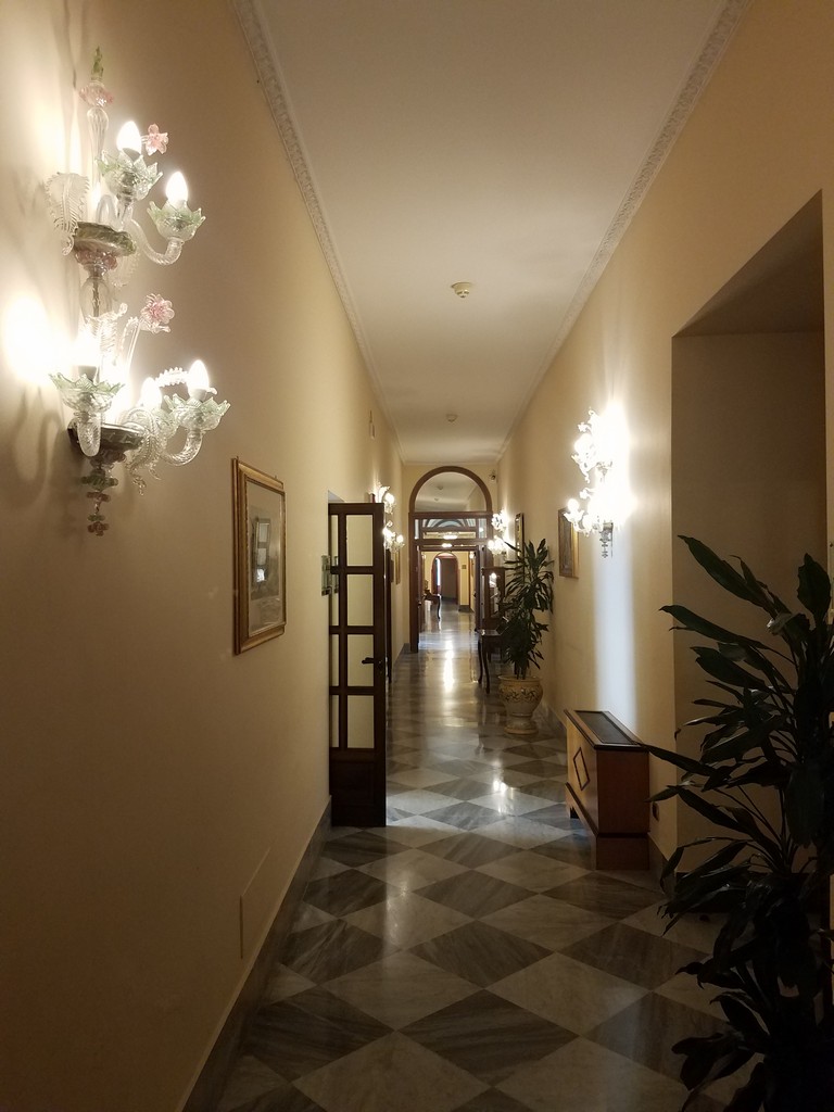 a hallway with sconces and a plant