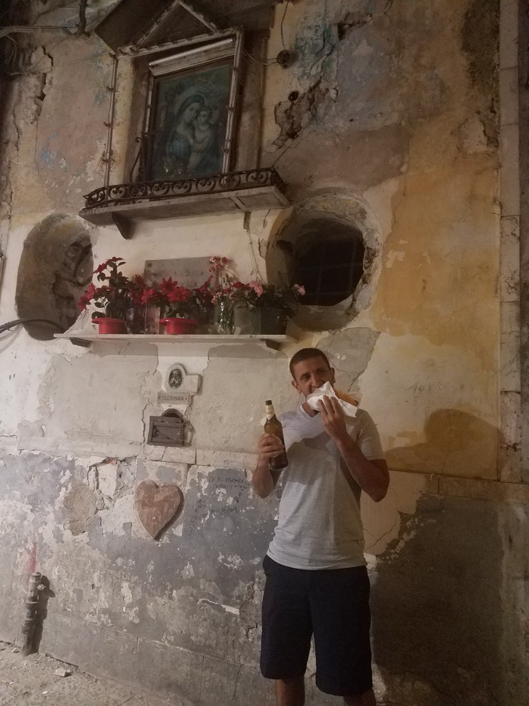 a man holding a bottle and napkin in front of a wall