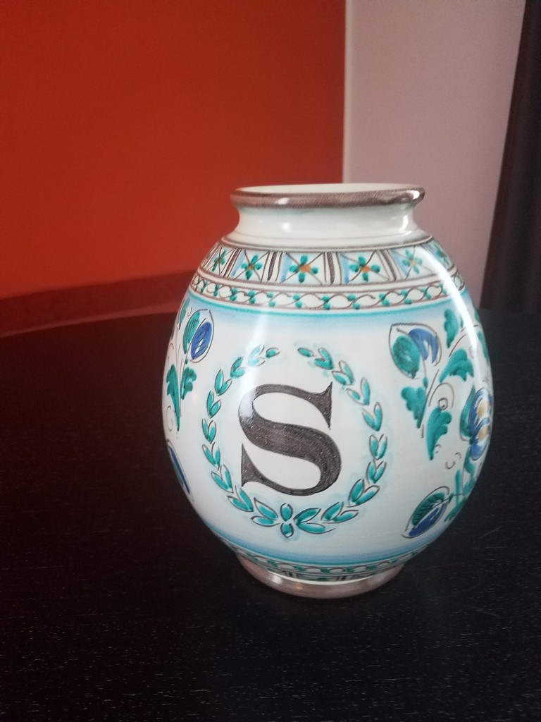 a vase with a letter on it