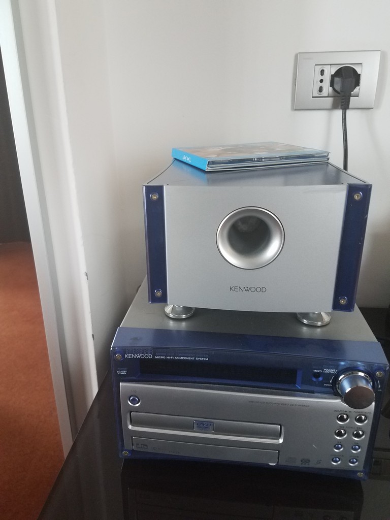 a silver and blue stereo on top of a stack of cd's