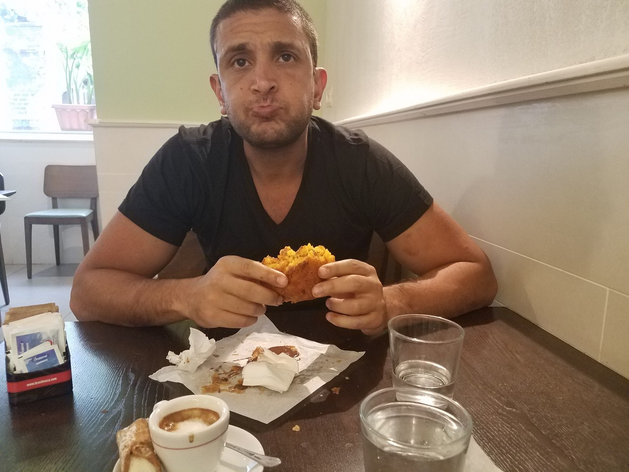 a man sitting at a table eating a sandwich