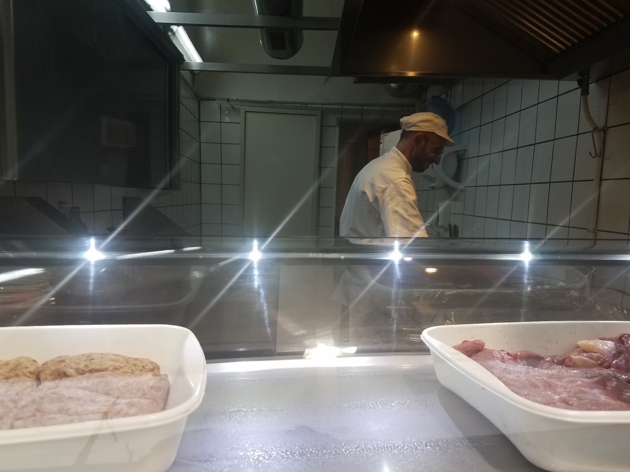 a man in a white hat in a kitchen with food in containers