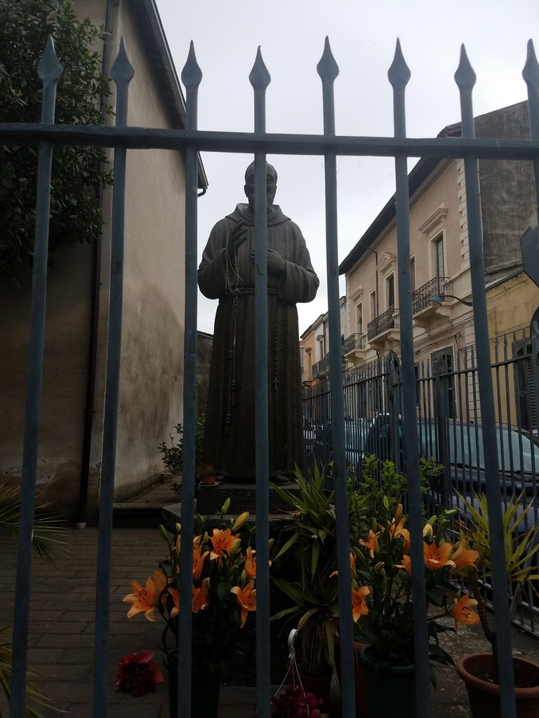a statue of a man in a robe behind a fence
