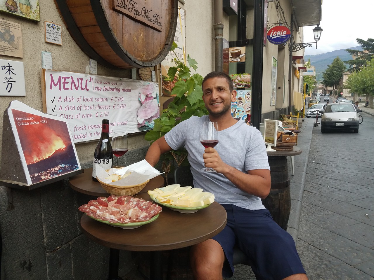 a man sitting at a table with food and wine