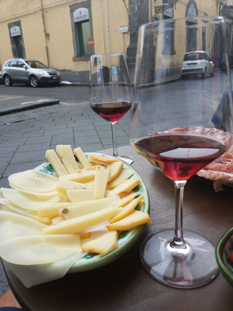 a plate of cheese and wine glasses on a table