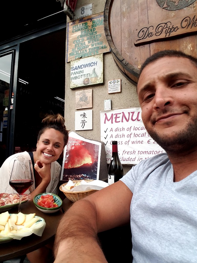 a man and woman sitting at a table with food and wine
