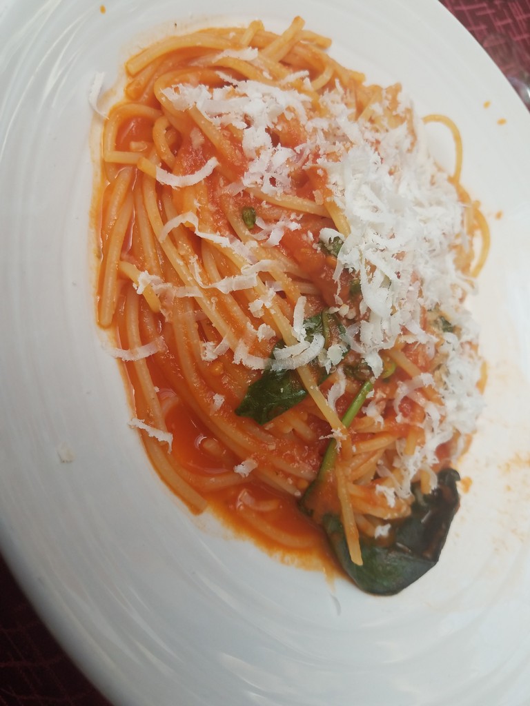a plate of spaghetti with cheese and basil