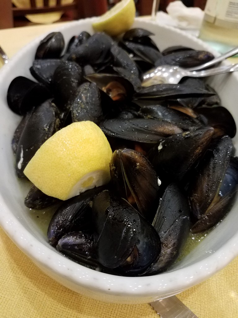 a bowl of mussels with a lemon wedge