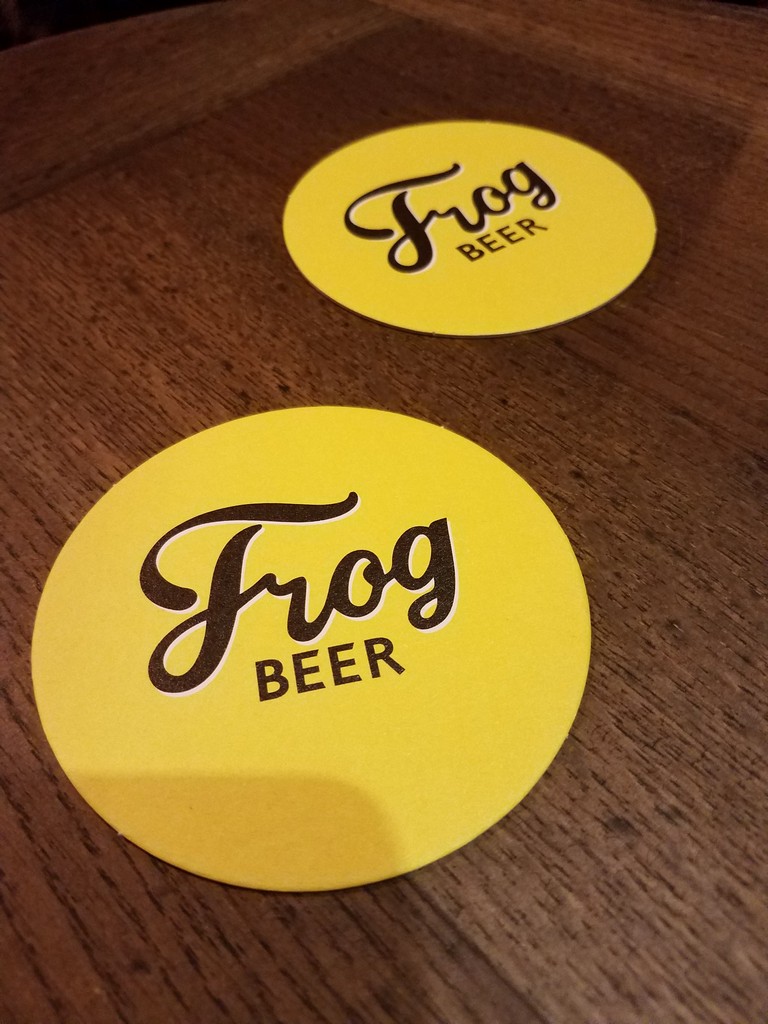 a pair of yellow beer coasters on a wooden surface