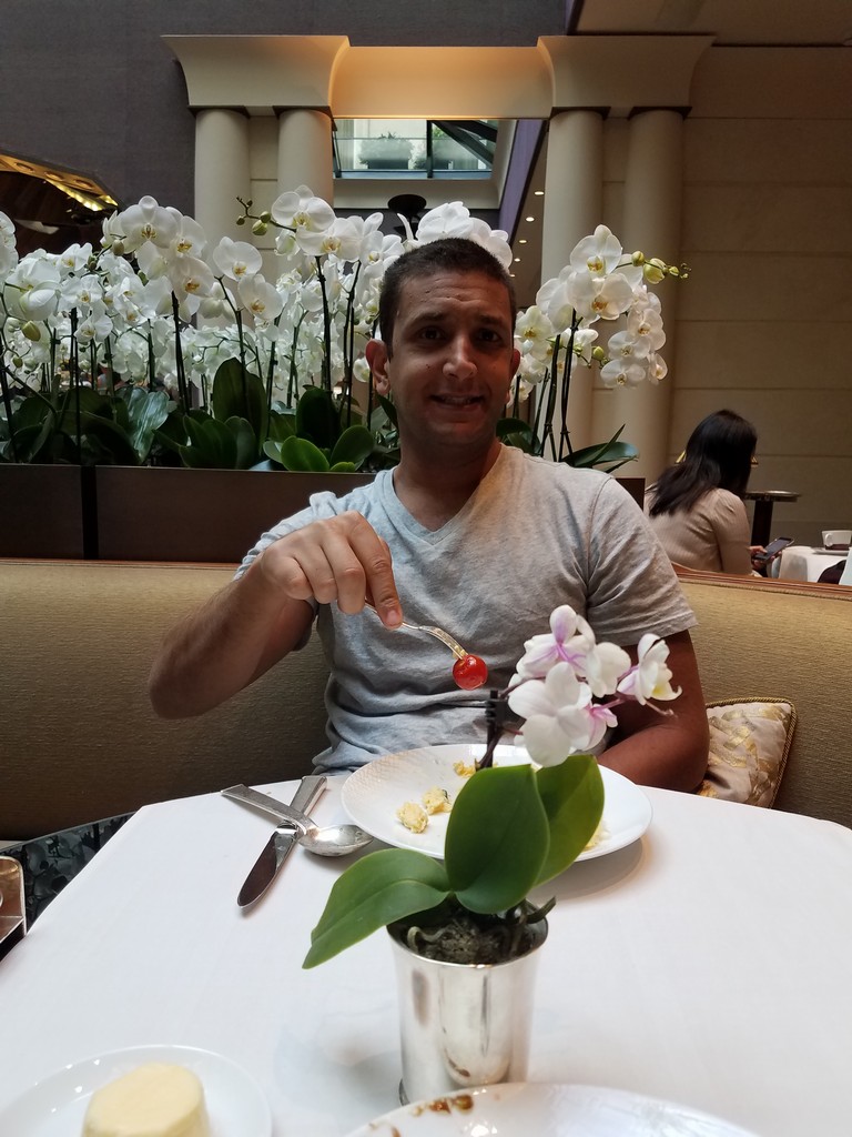 a man sitting at a table with a plate of food and a flower