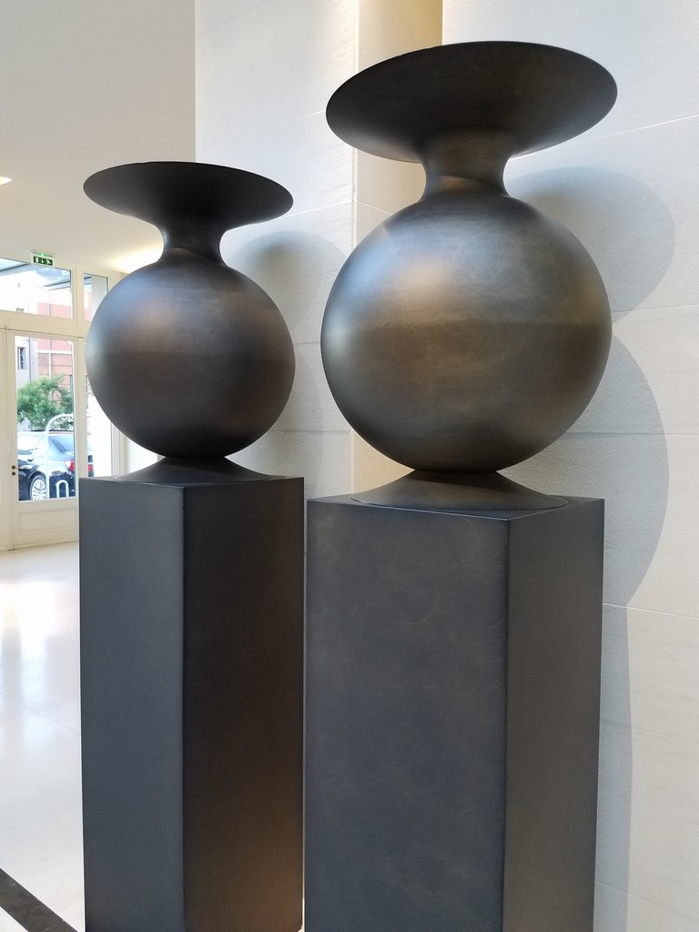 a pair of black vases on pedestals