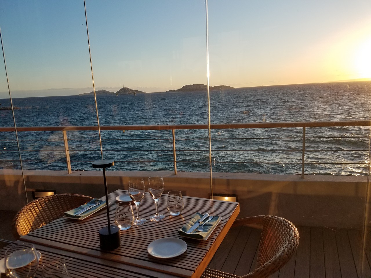 a table with plates and glasses on a deck overlooking water