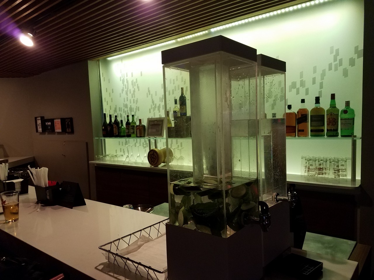 a bar with a glass container and bottles