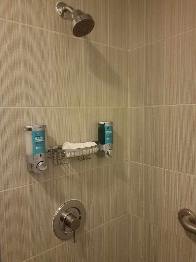 a shower with a shower head and soap dispenser