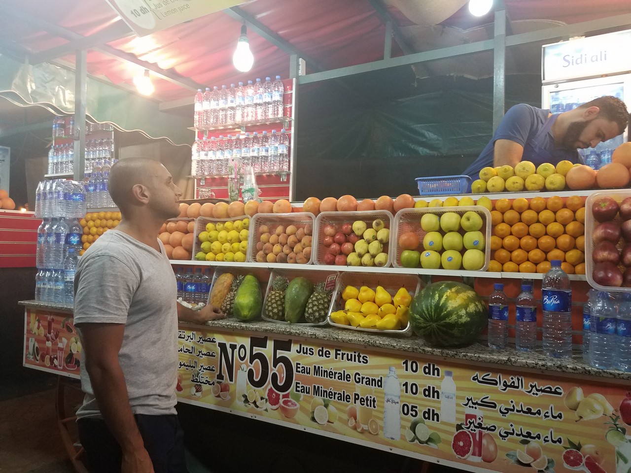 a man standing in front of a fruit stand