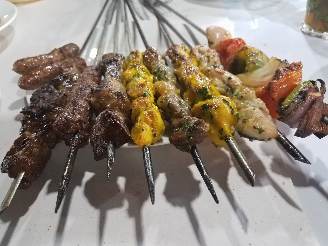 a plate of skewers of meat and vegetables