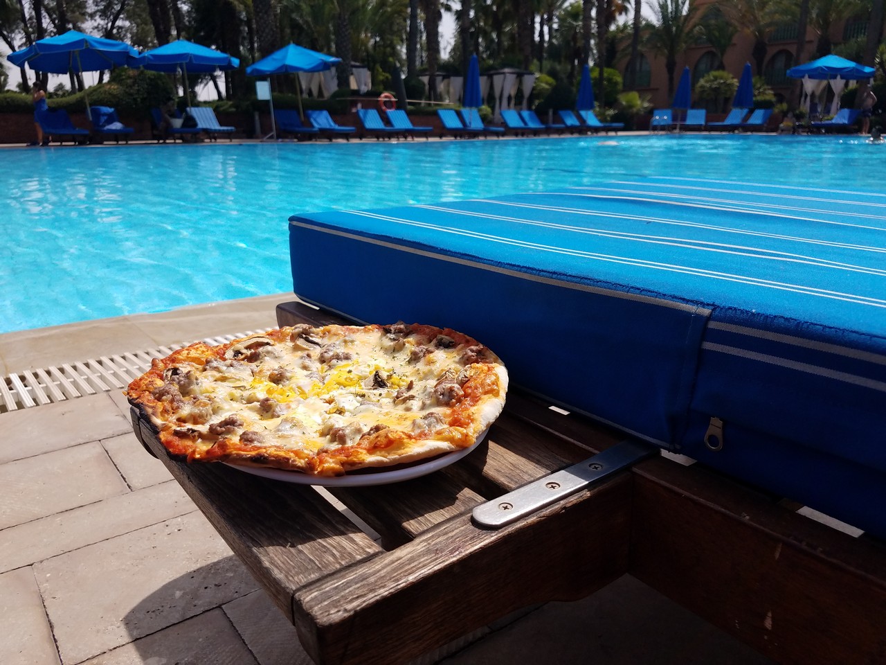 a pizza on a table next to a pool