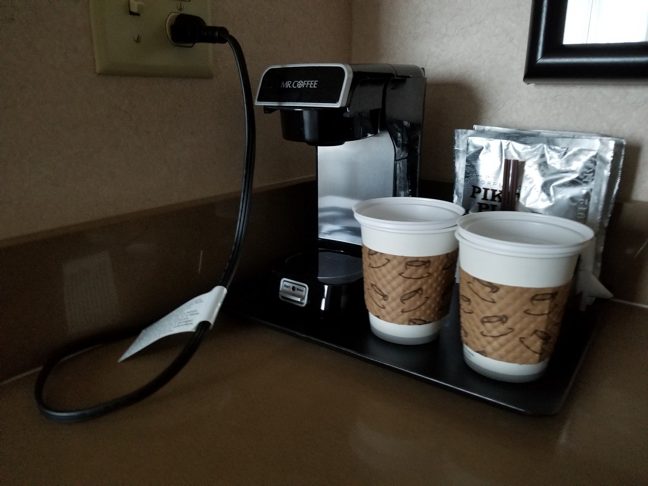 a coffee maker with two cups on a tray
