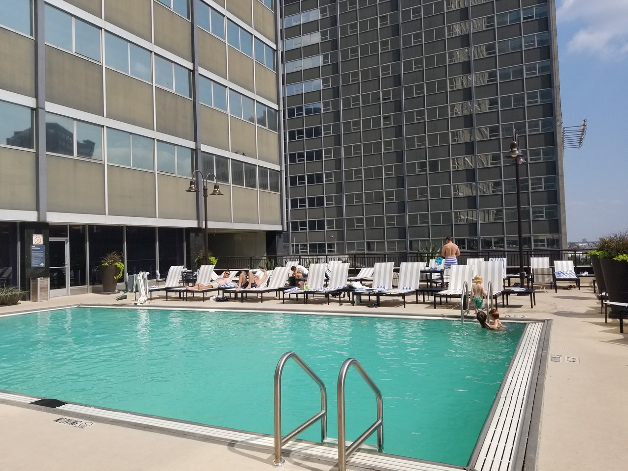 a pool with lounge chairs and people in it