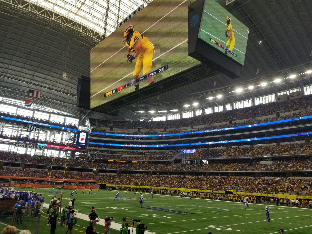a large screen in a stadium with AT&T Stadium in the background