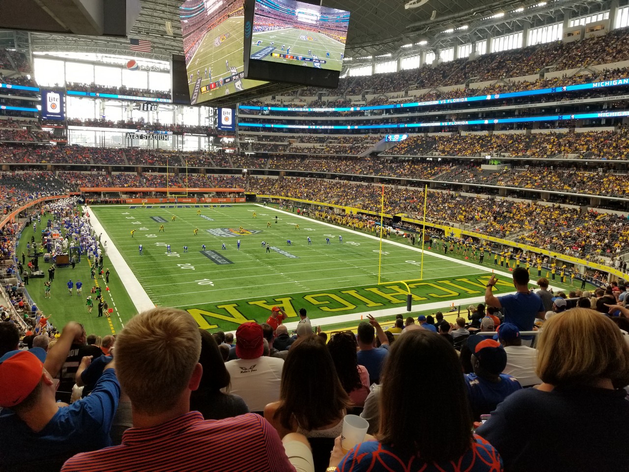 a football stadium with people watching a game with AT&T Stadium in the background