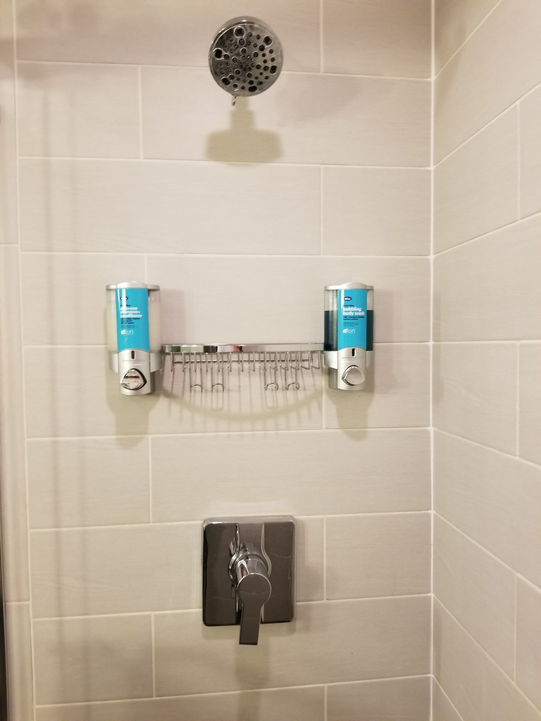 a shower with a shower head and soap dispensers