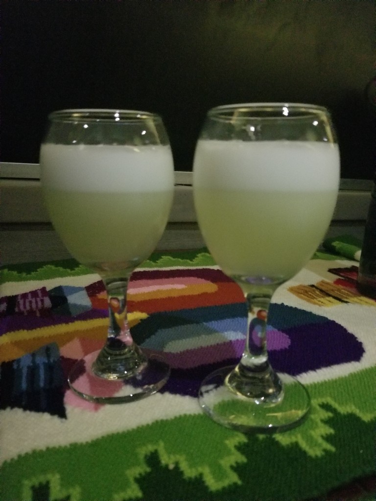 two glasses of white liquid on a colorful tablecloth