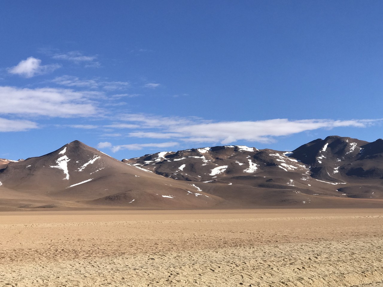 a desert landscape with mountains and blue sky