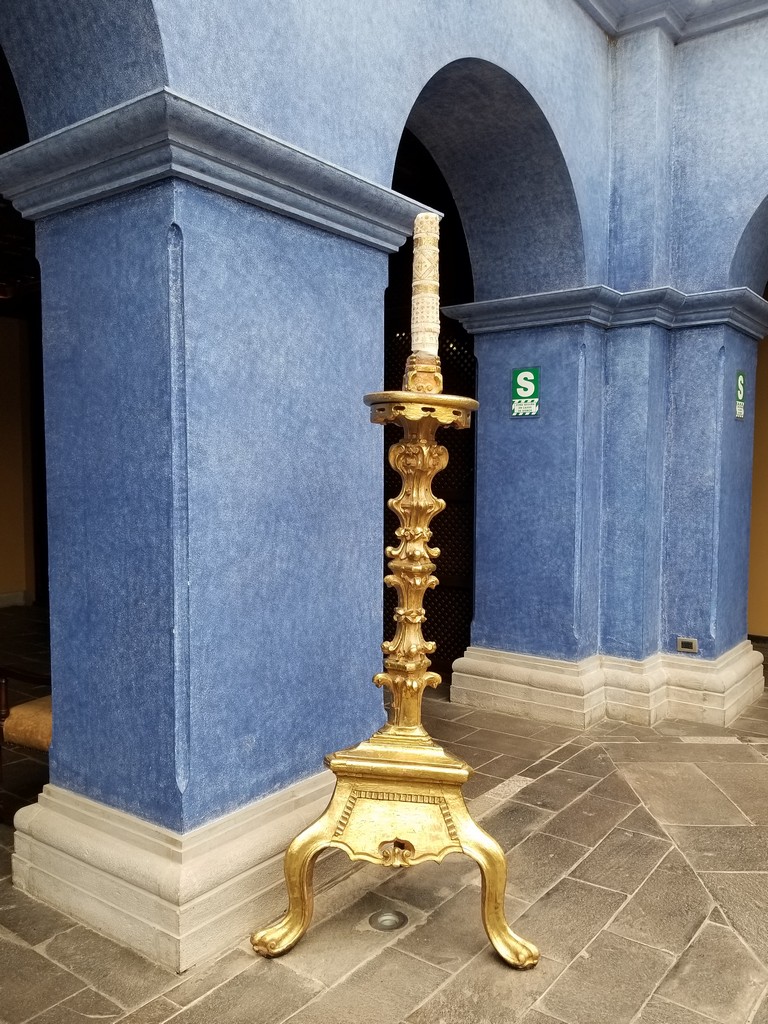 a gold candle holder in front of a blue wall