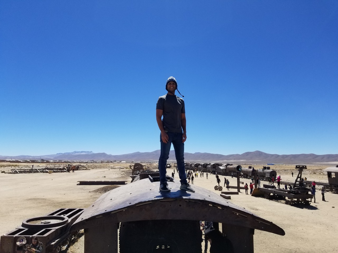 a man standing on top of a metal object in a desert