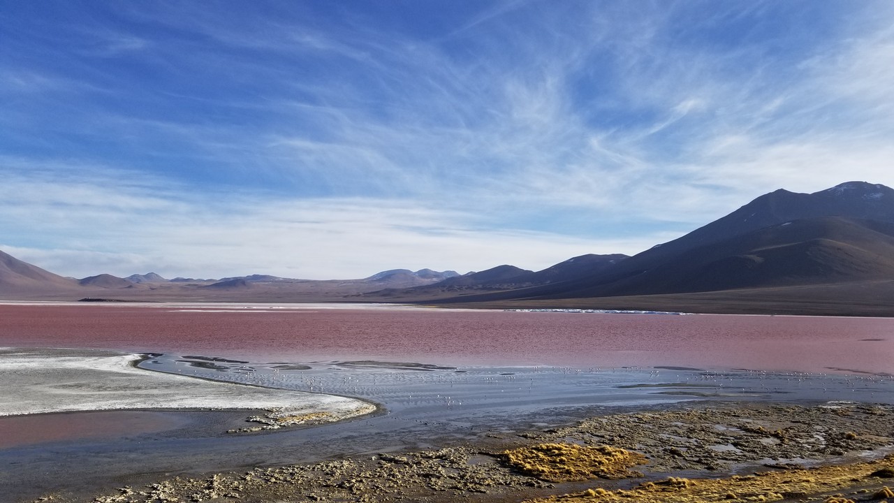 a red lake with mountains in the background