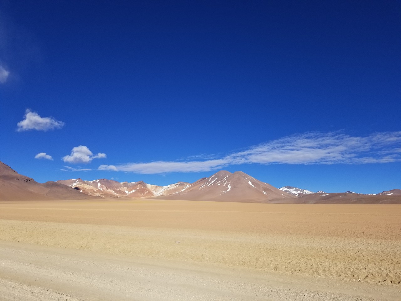 a sandy desert with mountains in the background
