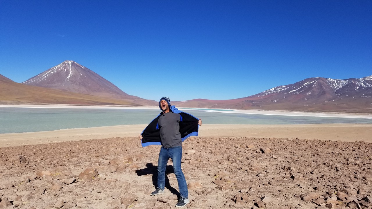 a man standing in a desert with a blue jacket