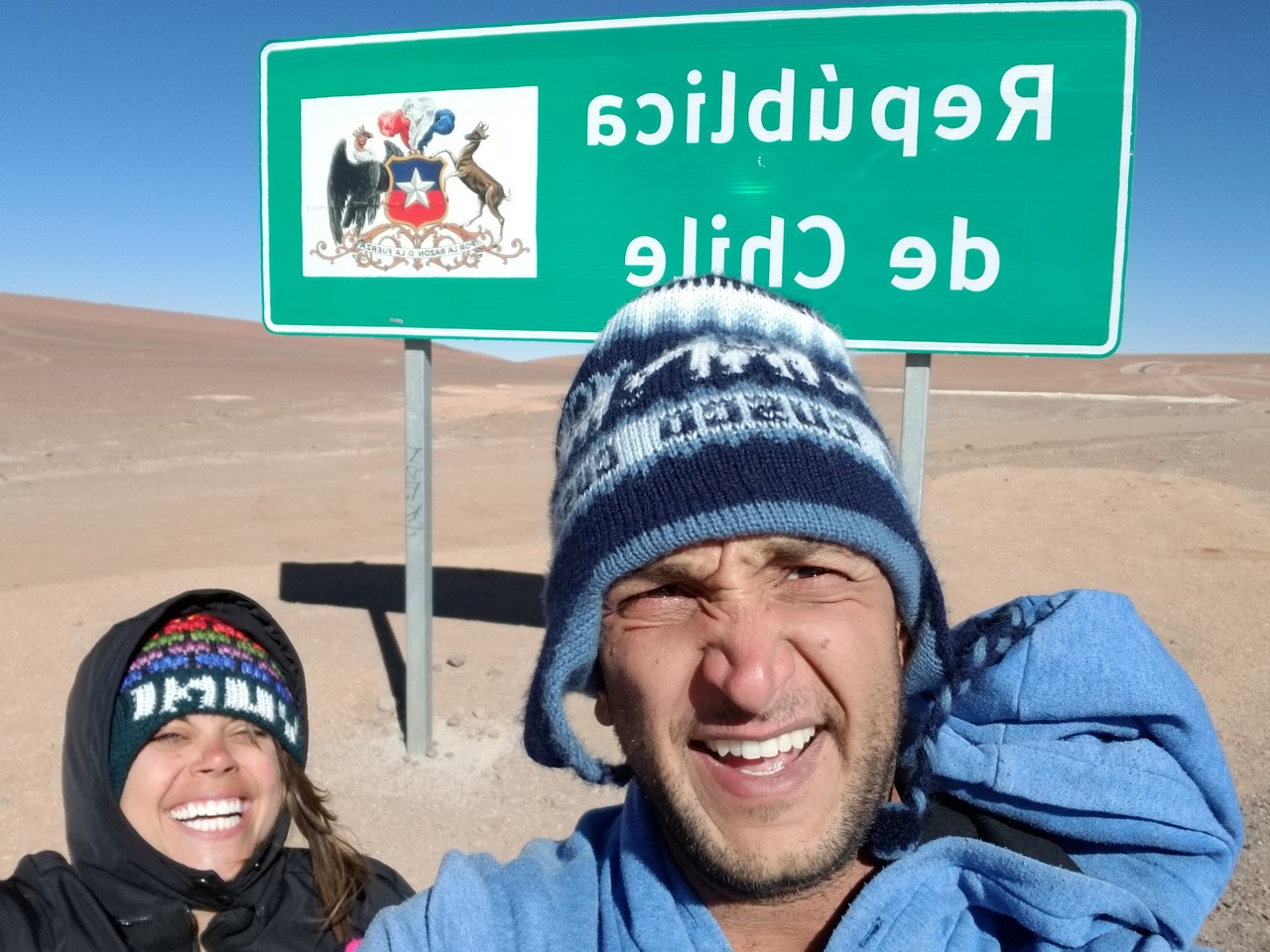 a man and woman taking a selfie in front of a sign