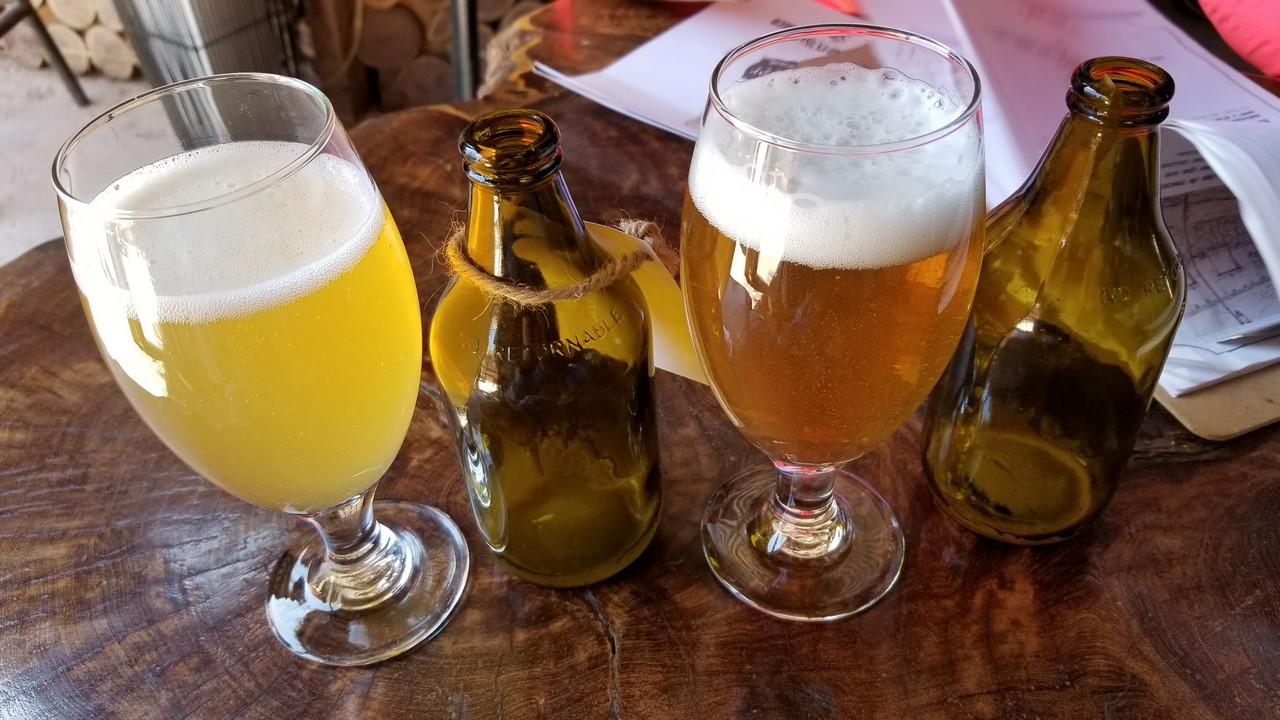 a group of glasses of beer and a bottle on a table