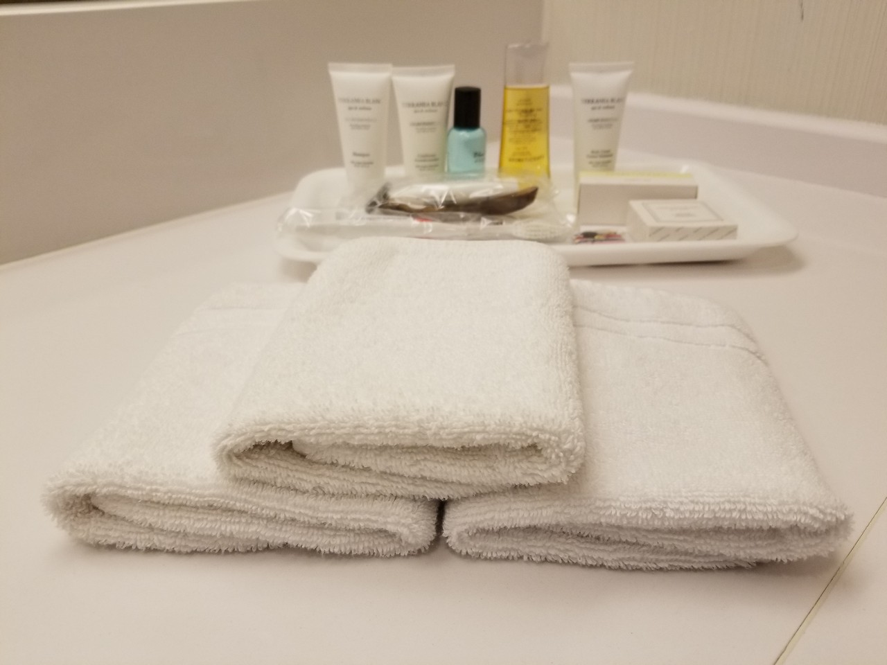 a tray with towels and a tray with small bottles of cosmetics