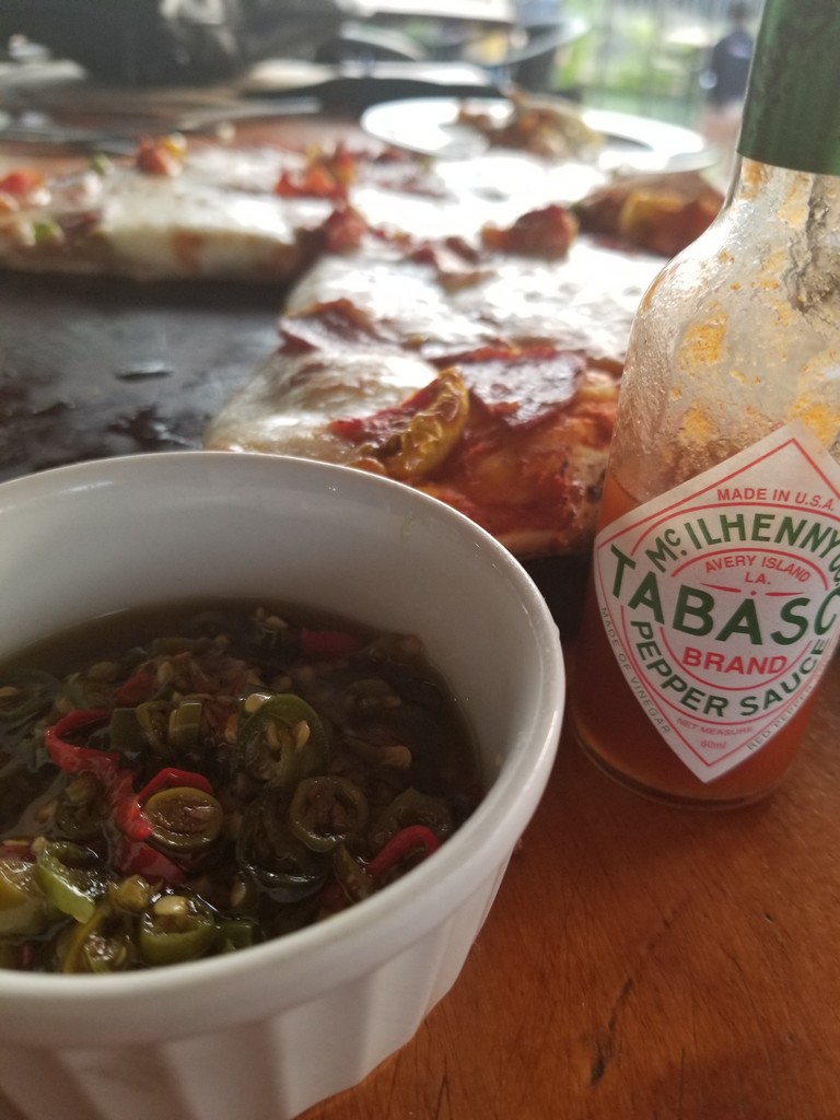 a bowl of food next to a bottle of hot sauce