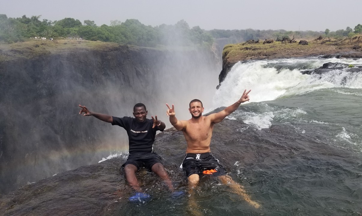 two men sitting in water with Victoria Falls