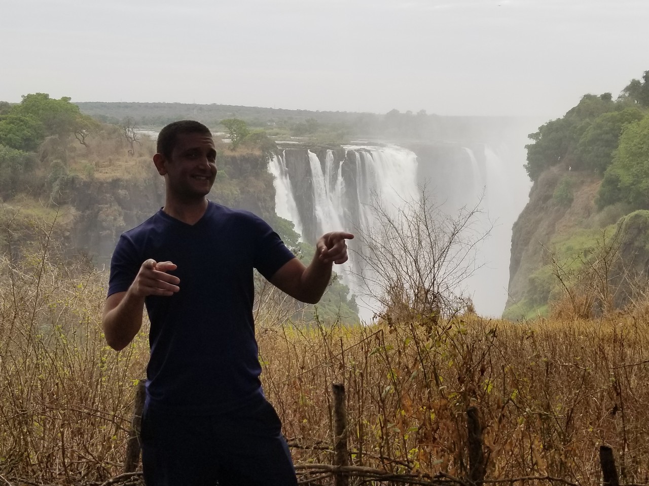 a man pointing at a waterfall