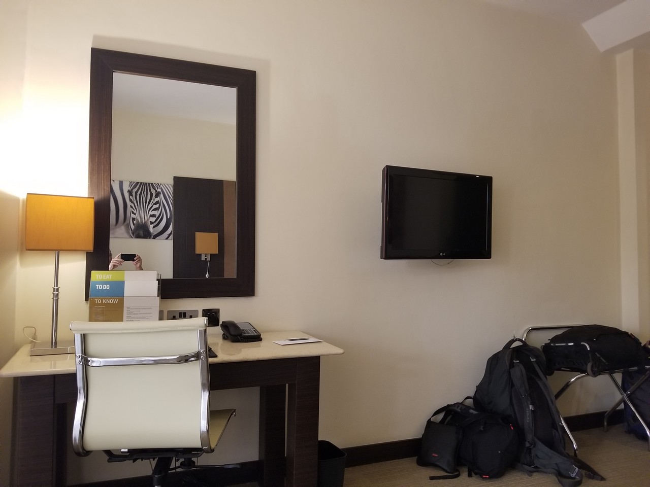 a room with a desk chair and a mirror and a television