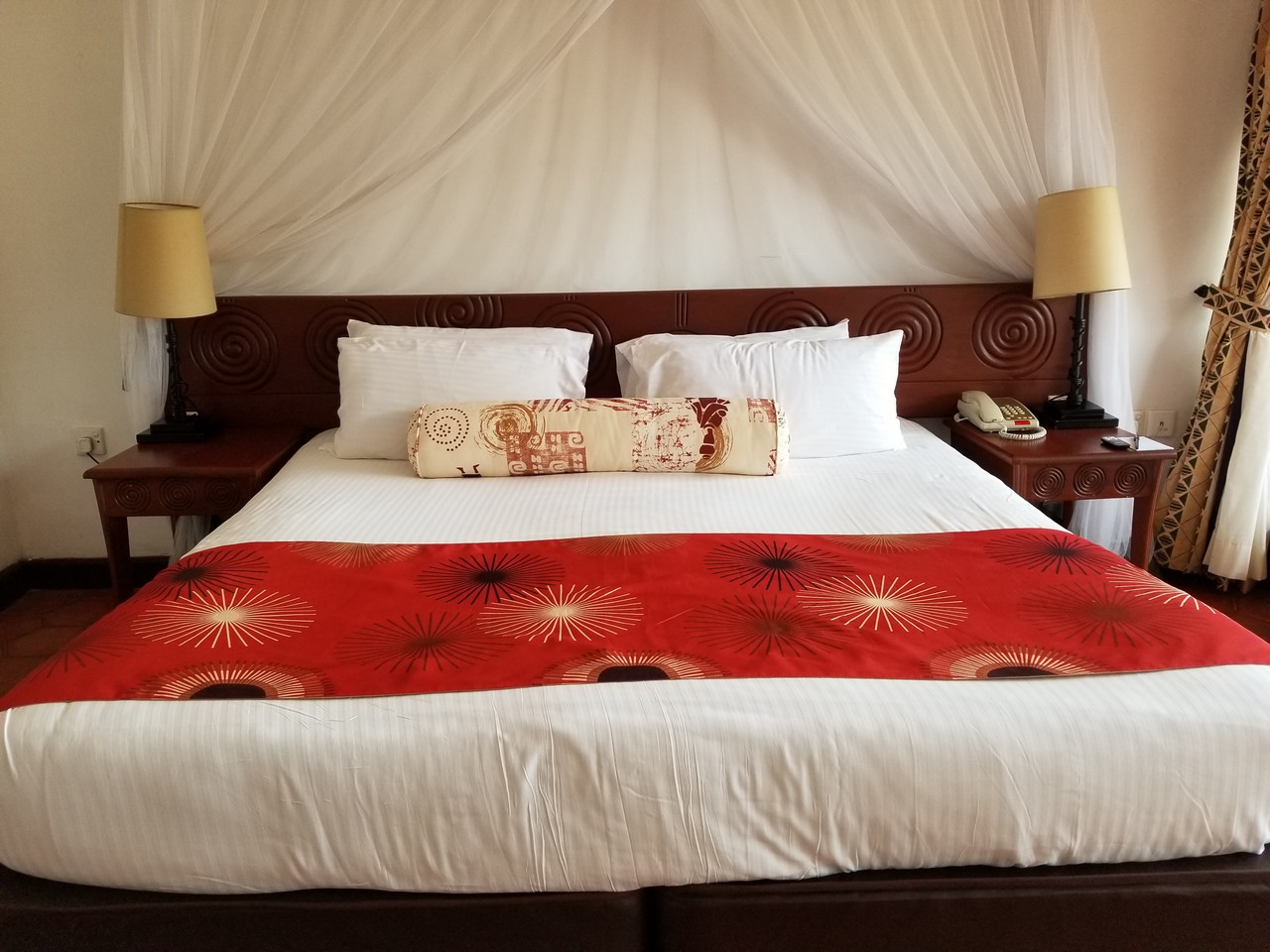 a bed with a red blanket and lamps