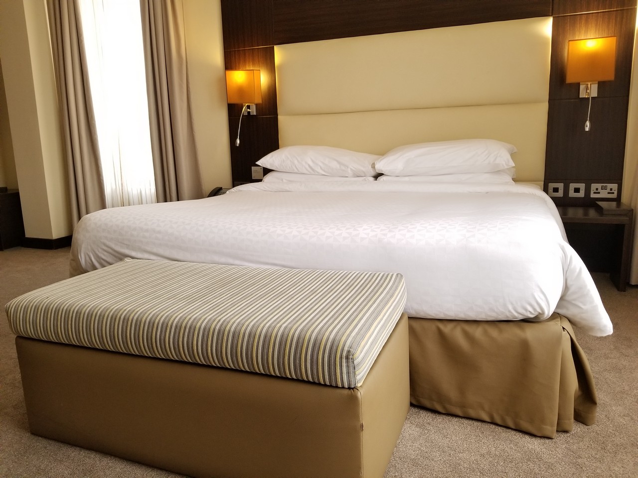 a bed with a foot stool in a hotel room