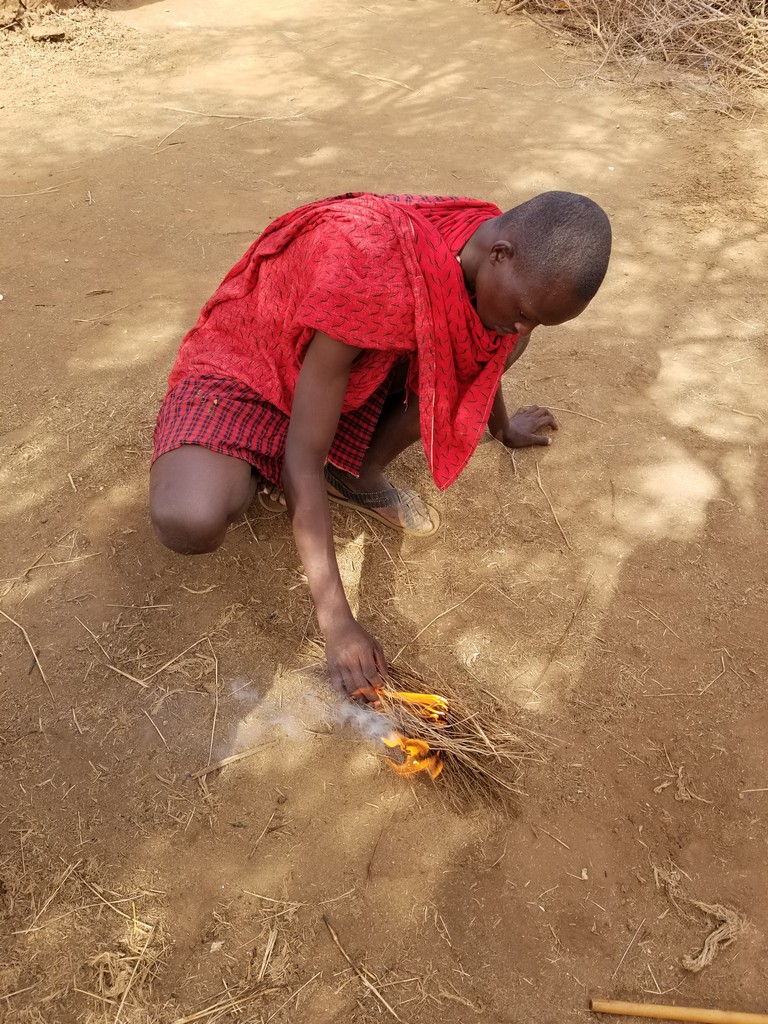 a man kneeling on the ground holding a fire