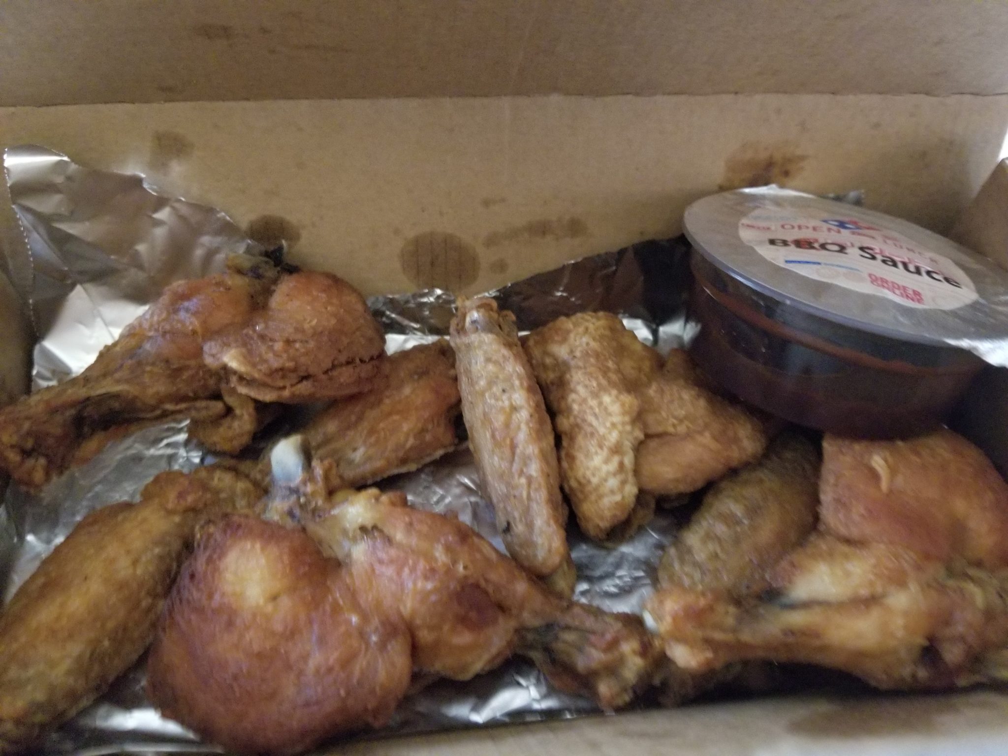 a box of chicken wings and a container of sauce
