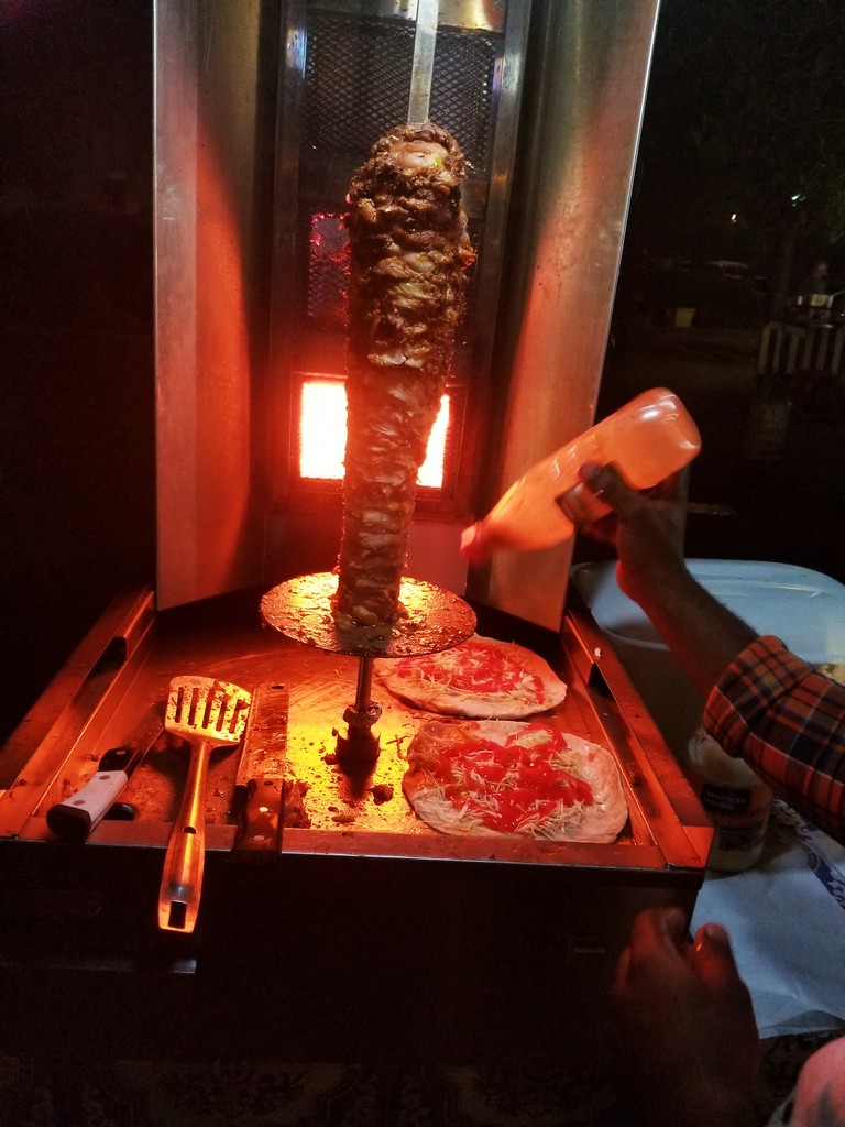 a man pouring a bottle of sauce on a meat on a grill