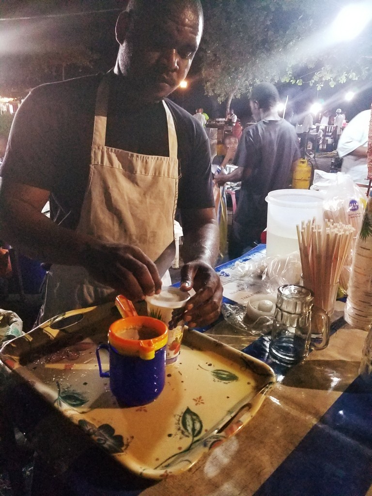 a man in an apron pouring food into a tray