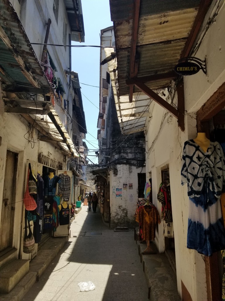 a narrow alley between buildings with clothes on the wall