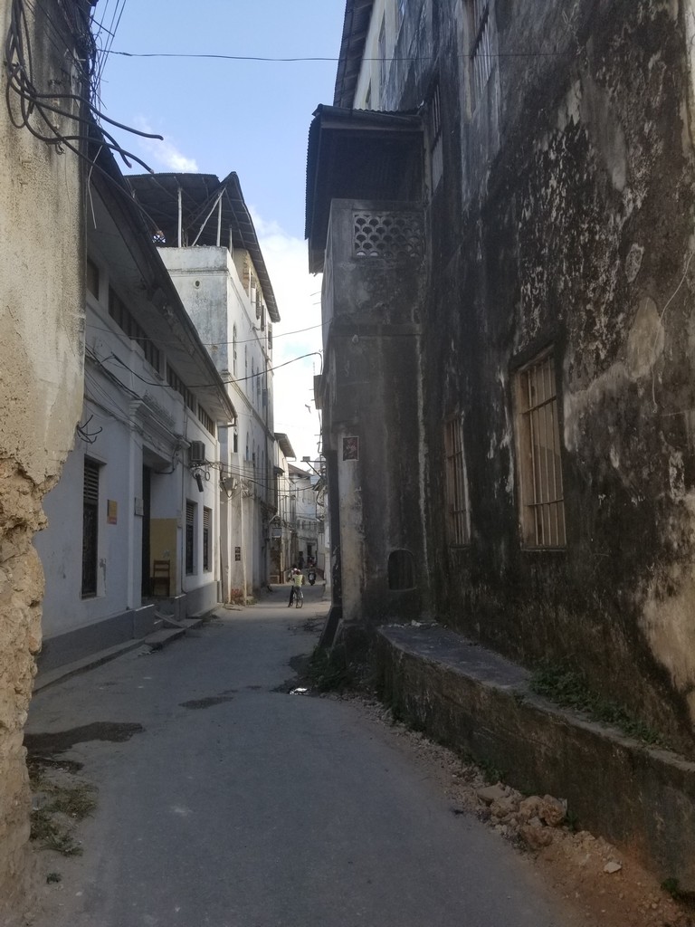 a narrow street with buildings and people on the side